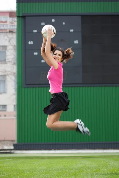 Fille pom-pom girls sauter avec un ballon de football — Photo