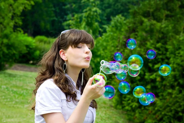 Young girl blowing soap bubbles in spring green — Stock Photo, Image