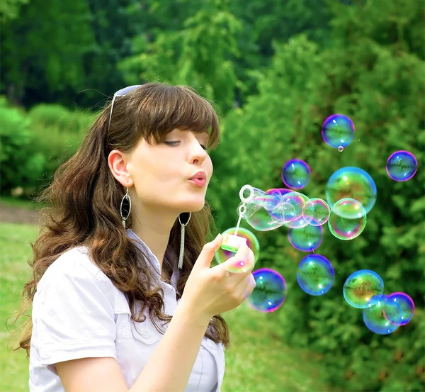 Young girl blowing soap bubbles in spring green — Stock Photo, Image
