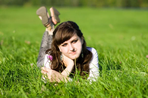 Jonge volwassen mooi meisje liggen in gras — Stockfoto