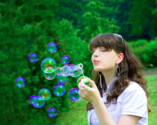 Jong meisje blazen van zeepbellen in het voorjaar groen — Stockfoto