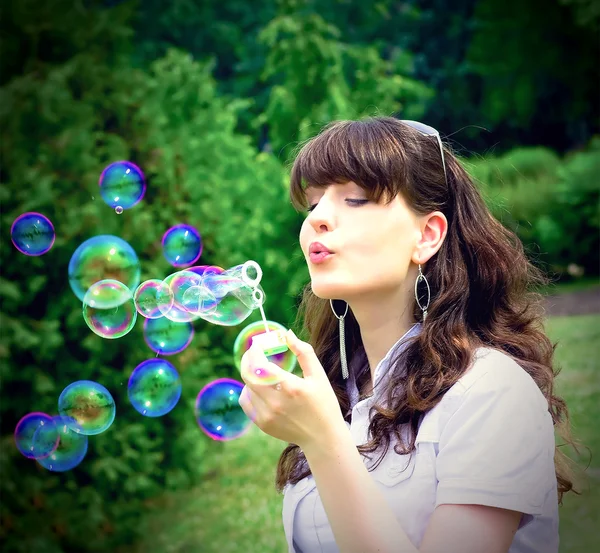 Девушка надувает пузыри весной — стоковое фото