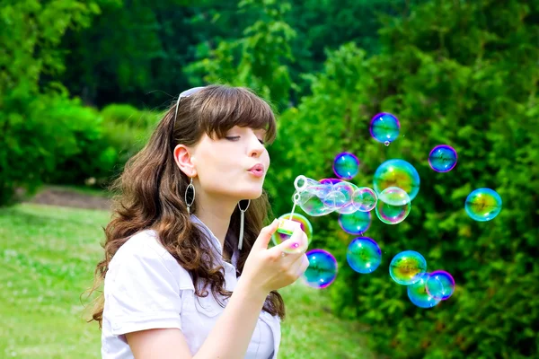 Девушка надувает пузыри весной — стоковое фото