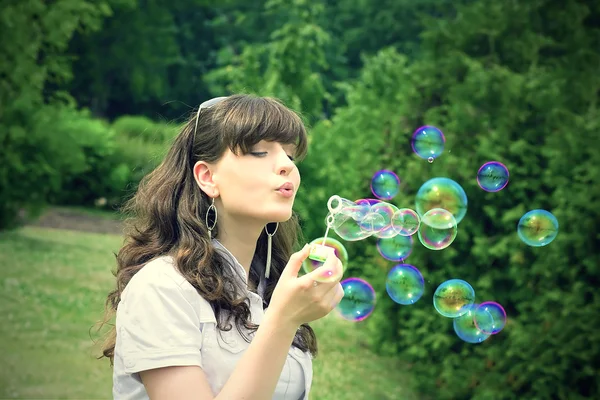 Úsměv teen s mýdlové bubliny v živé zelené jaro forest park — Stock fotografie