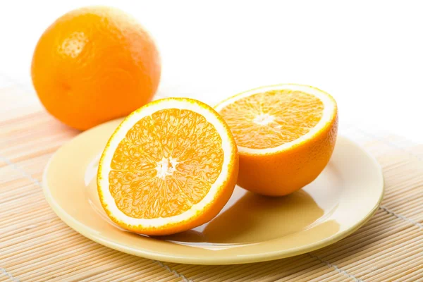 Ripe oranges in yellow plate isolated — Stock Photo, Image