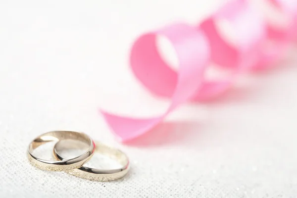 Golden wedding rings and pink ribbon — Stock Photo, Image