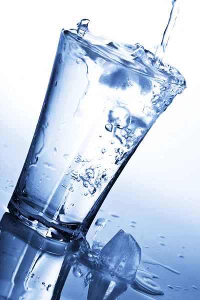 Acqua spruzzata in vetro con cubetti di ghiaccio Foto Stock