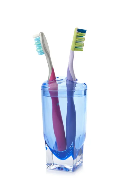 Duas escovas de dentes coloridas em vidro isolado — Fotografia de Stock