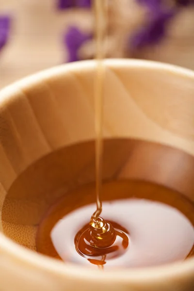 Wild honey pouring into wooden bowl — Stock Photo, Image