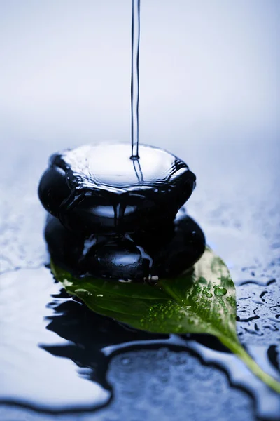 Water splashing over zen stone on leaf — Stock Photo, Image
