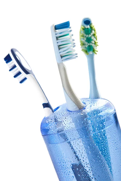 Τρεις οδοντόβουρτσες σε ποτήρι απομονωθεί — Φωτογραφία Αρχείου