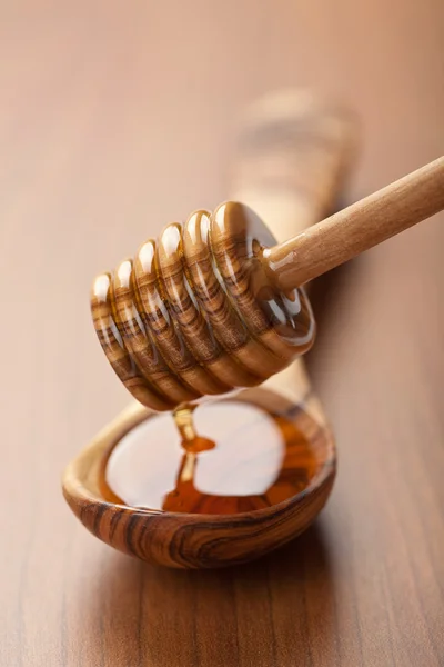Дикий мед, льющийся в деревянную ложку из ковша — стоковое фото