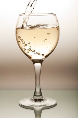 beyaz şarap bardağa dökülüyor.