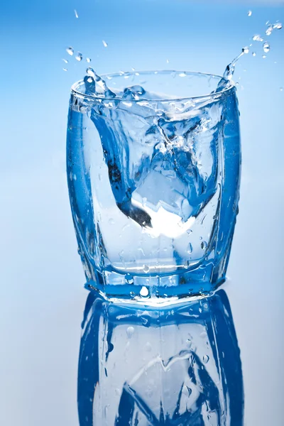 Ледяной куб брызгает в стакан воды — стоковое фото