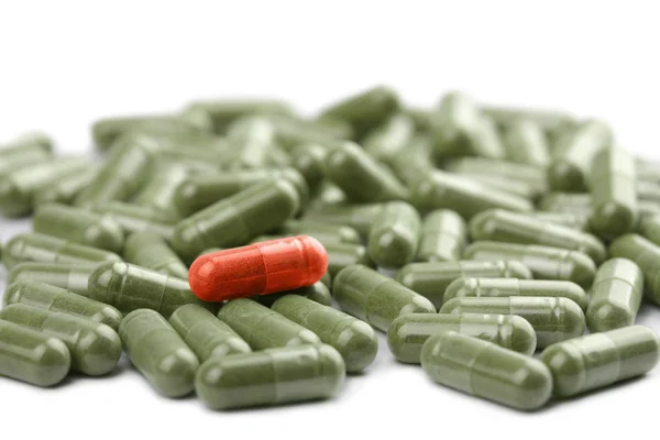 Zelená tobolka pilulek s červenou, jeden samostatný — Stock fotografie