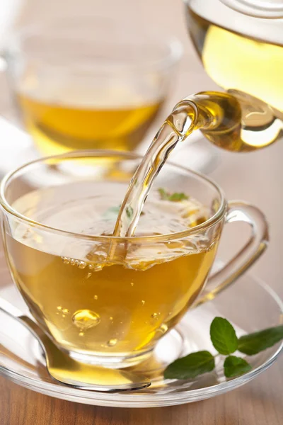 Зеленый чай наливается в стеклянную чашку — стоковое фото