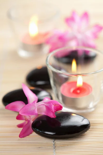 Spa-kövek és a rózsaszín virágok, mint bambusz mat — Stock Fotó