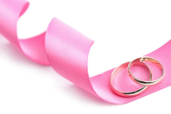 Anéis de casamento dourados sobre fita rosa isolada — Fotografia de Stock