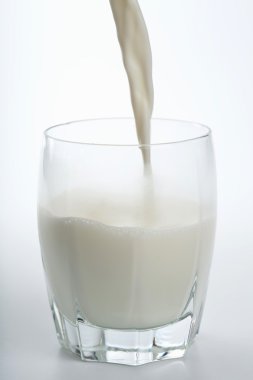 Milk pouring into glass isolated clipart