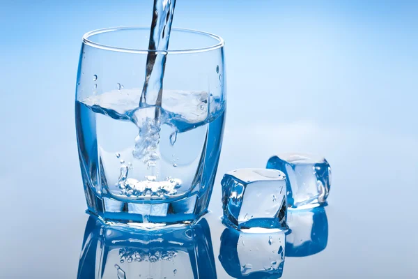 Agua salpicando en vidrio con cubitos de hielo — Foto de Stock