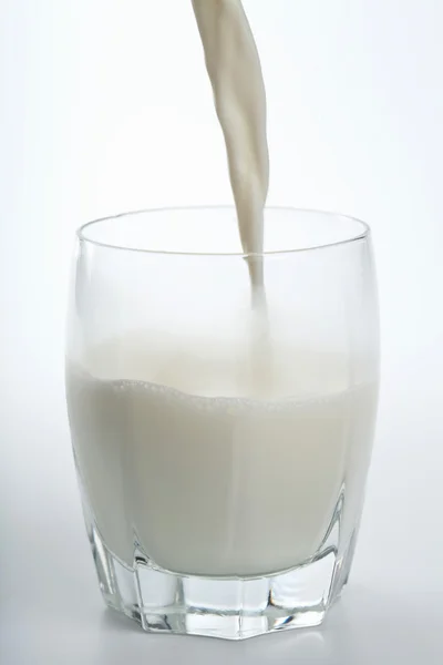 Γάλα που ρίχνει στο ποτήρι απομονωθεί — Φωτογραφία Αρχείου