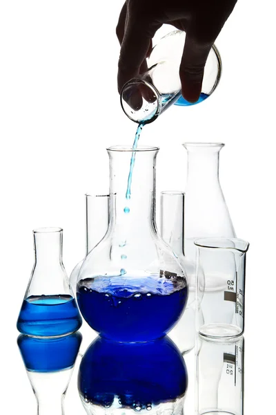 Ręka, wlewając niebieski płyn Chemia do kolby na białym tle — Zdjęcie stockowe