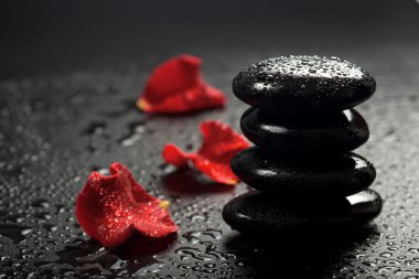 Spa stones and rose petals over black background clipart
