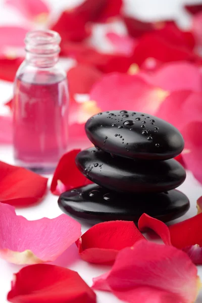 Piedras de spa, aceite esencial y pétalos de rosa —  Fotos de Stock