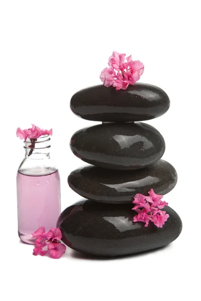 Pedras de spa com flores e garrafa cosmética isolada — Fotografia de Stock