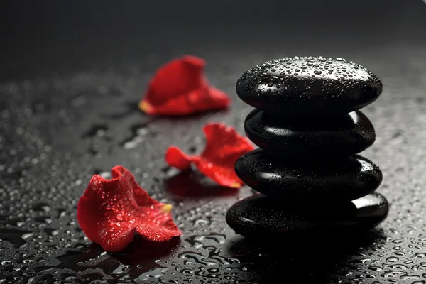Pedras de spa e pétalas de rosa sobre fundo preto — Fotografia de Stock