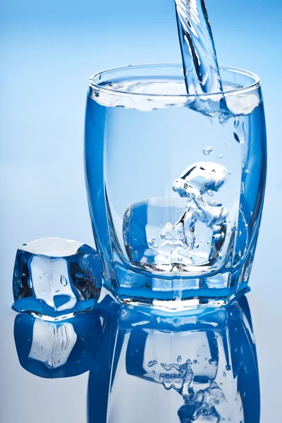 Vatten stänk i glas med isbitar — Stockfoto
