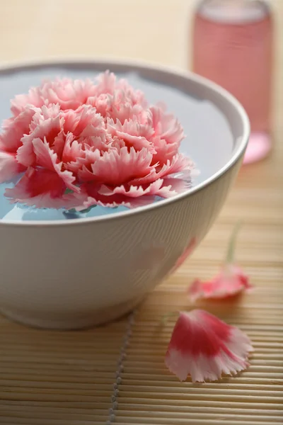 Fleur dans un bol et bouteille cosmétique — Photo