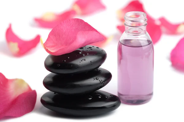Wellness stones, etherische olie en rozenblaadjes geïsoleerd — Stockfoto
