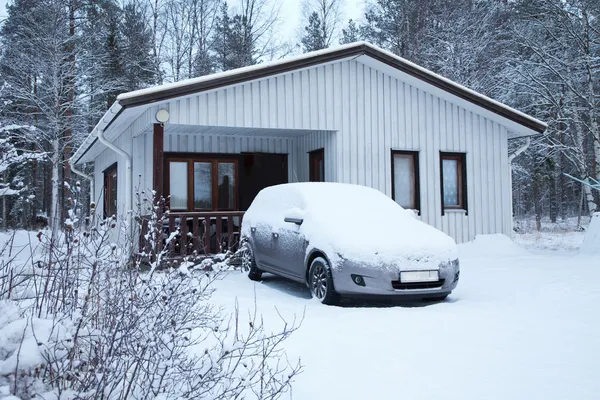 Auto lumen alla lähellä valkoista taloa — kuvapankkivalokuva