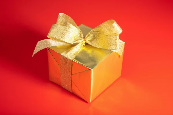 Fiyonklu kırmızı zemin üzerine altın hediye kutusu — Stok fotoğraf