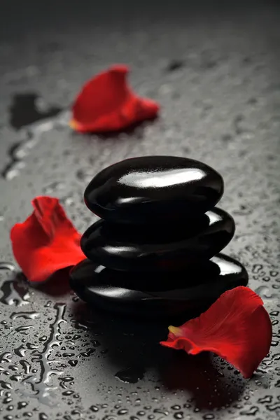 Pedras de spa e pétalas de rosa sobre fundo preto — Fotografia de Stock