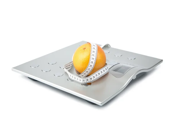 Orange and measuring tape over scales isolated — Stock Photo, Image