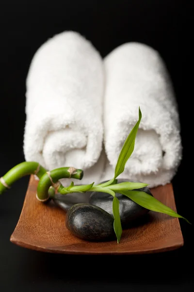 Pedras e toalhas de spa sobre preto — Fotografia de Stock