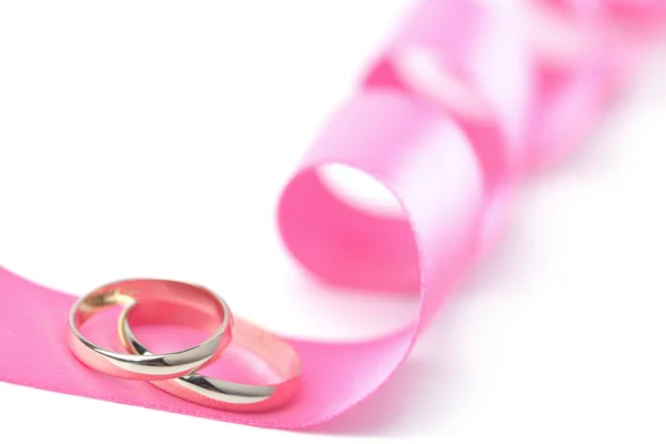 Anéis de casamento de ouro sobre fita rosa isolado — Fotografia de Stock