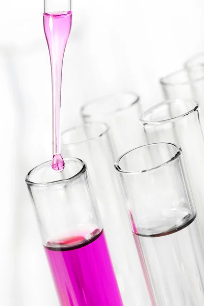 Liquid dripping from pipette into test tube — Stock Photo, Image