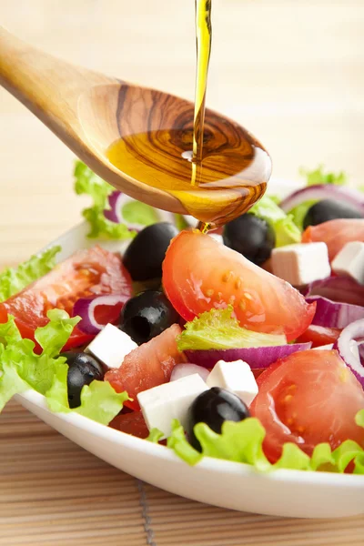 Olivenöl über Salat gießen — Stockfoto