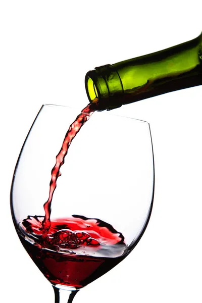 Красное вино, разливающееся в изолированный стакан — стоковое фото