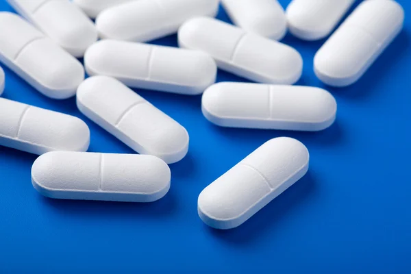 Білі таблетки над синім — стокове фото