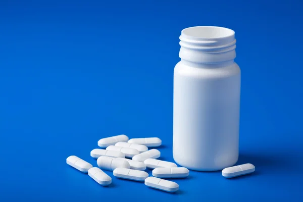 Pílulas brancas sobre azul — Fotografia de Stock