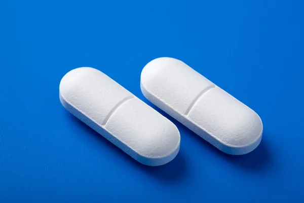 Белые таблетки над синим — стоковое фото