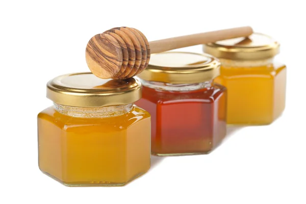 Мед в бутылках и деревянной ковши изолированы — стоковое фото