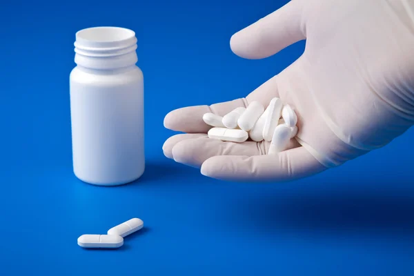 Mão segurando pílulas brancas — Fotografia de Stock