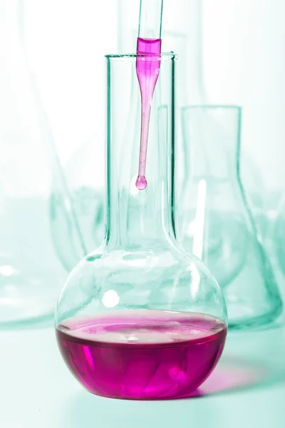Liquid dripping from pipette into flask — Stock Photo, Image