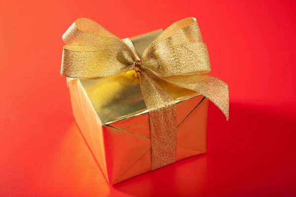 Caixa de presente dourada sobre fundo vermelho — Fotografia de Stock