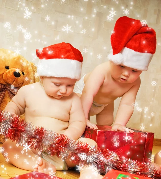 两个可爱幼儿在包装礼物的圣诞帽子 — 图库照片